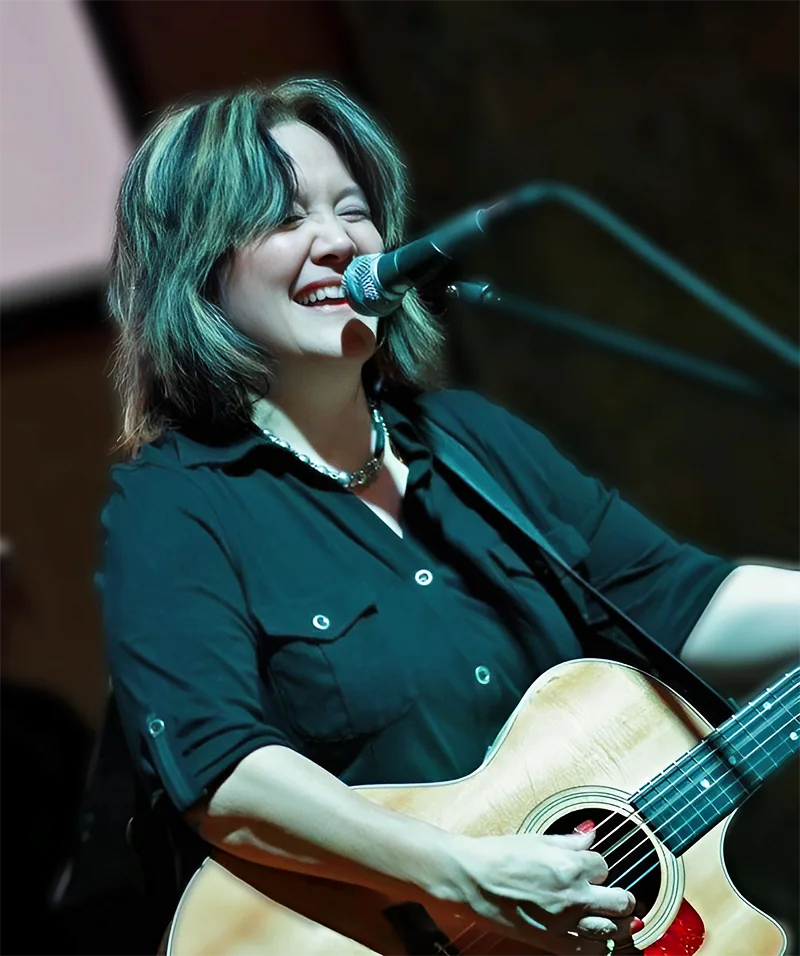 Kim-Char Meredith singing and playing acoustic guitar